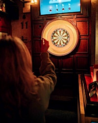 A woman aims to throw a dart at a dart board