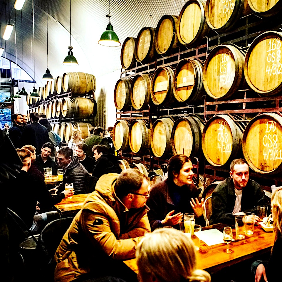 people seated by the barrels in the barrel project taproom in bermondsey london