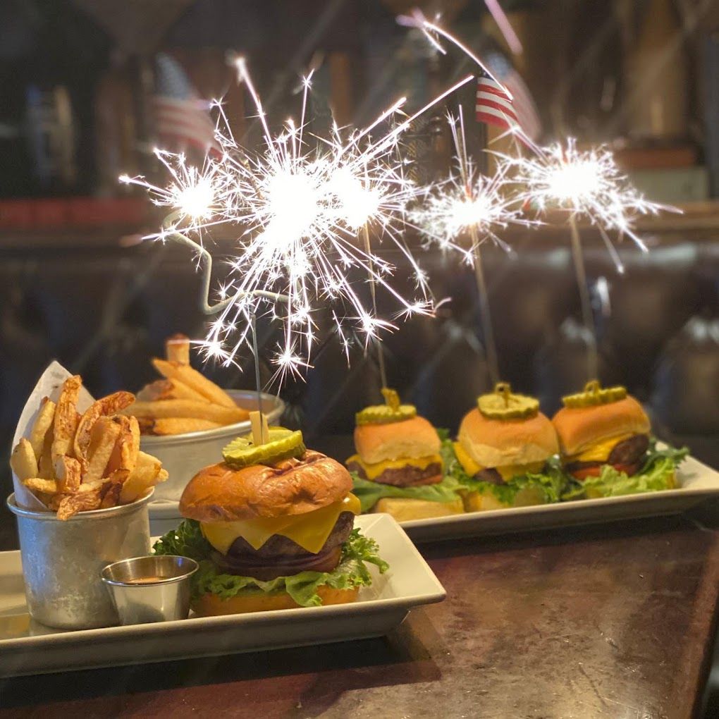 Cheeseburgers and fries with sparklers on top at Stout NYC at Penn Station, a sports bar in the city. 